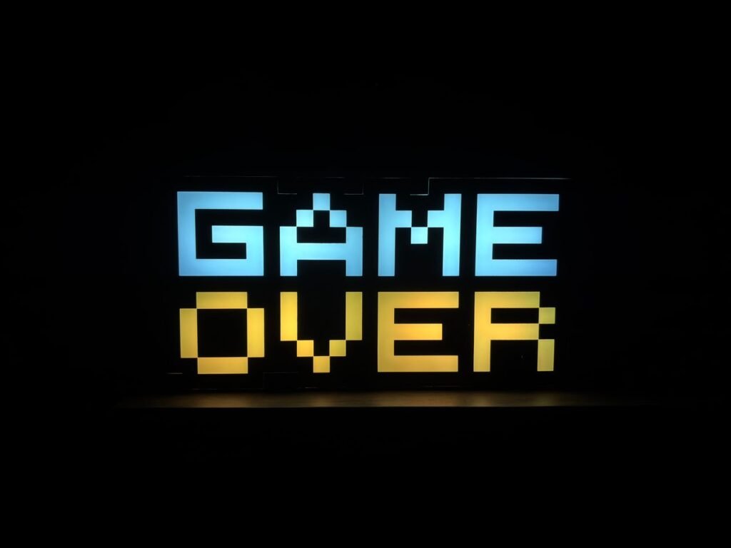 Illuminated pixel art 'Game Over' sign with vibrant colors against a black background.